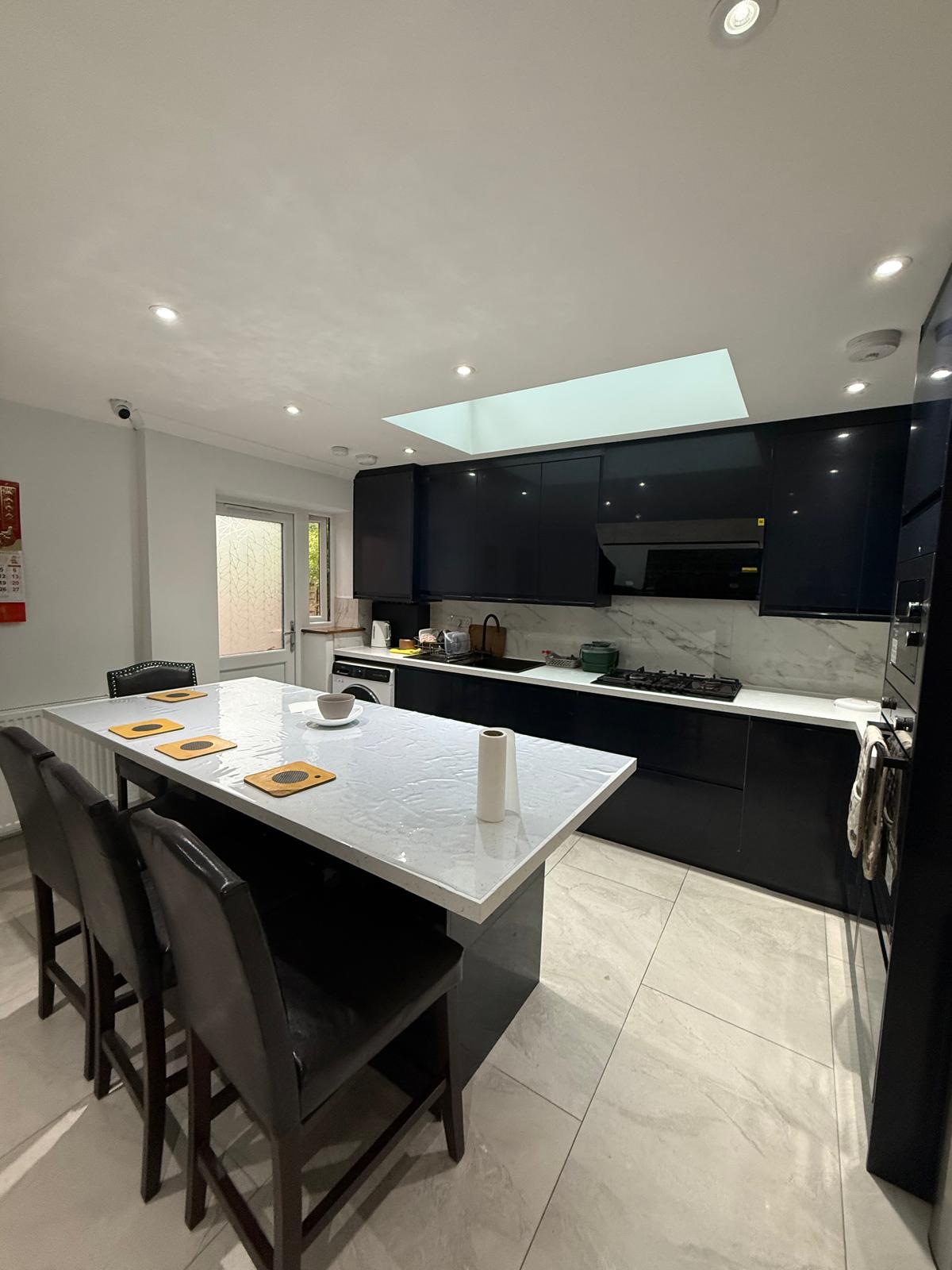 Navy gloss kitchen with skylight and marble breakfast bar